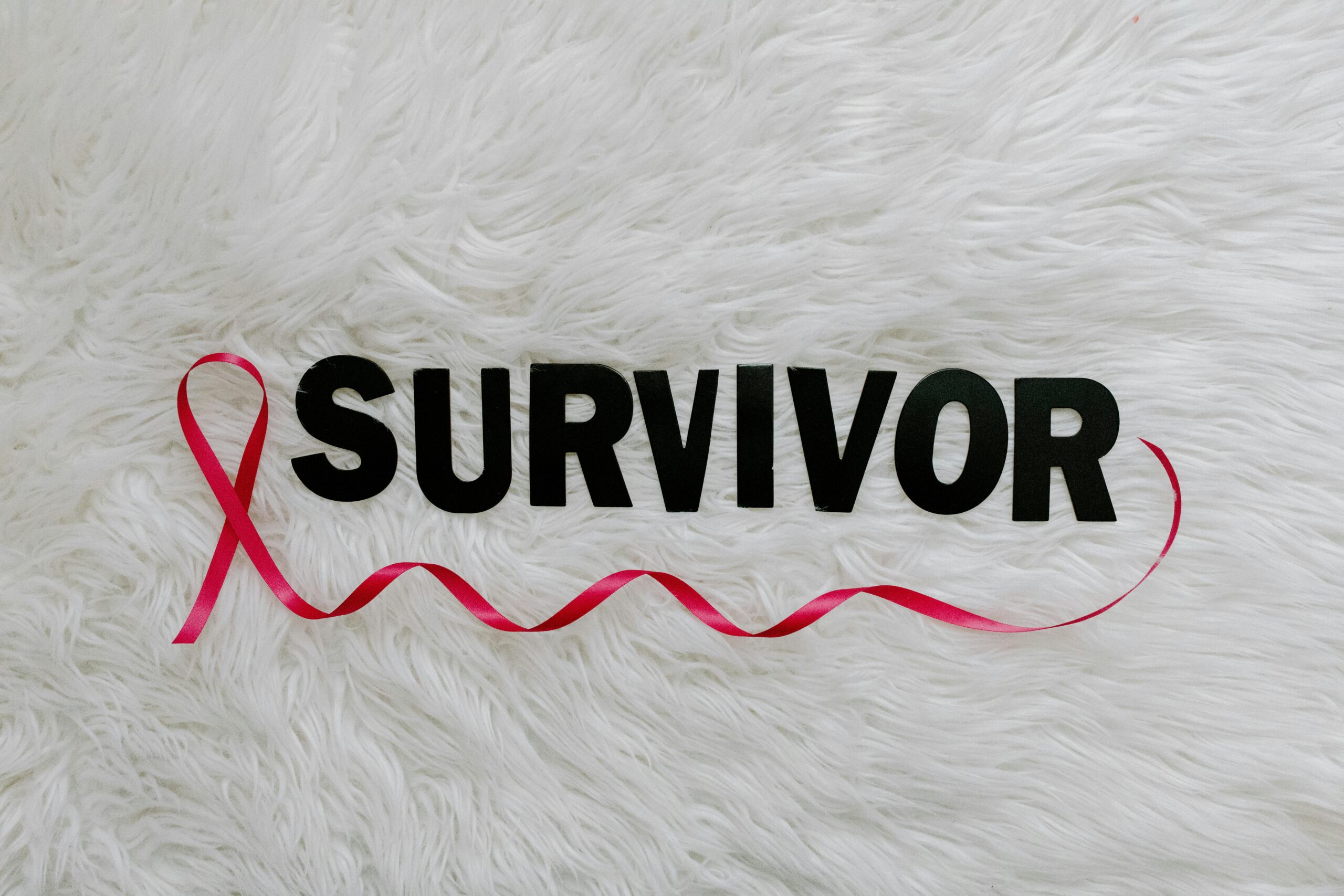 Inspirational image showcasing a pink ribbon next to SURVIVOR text on a soft white background.